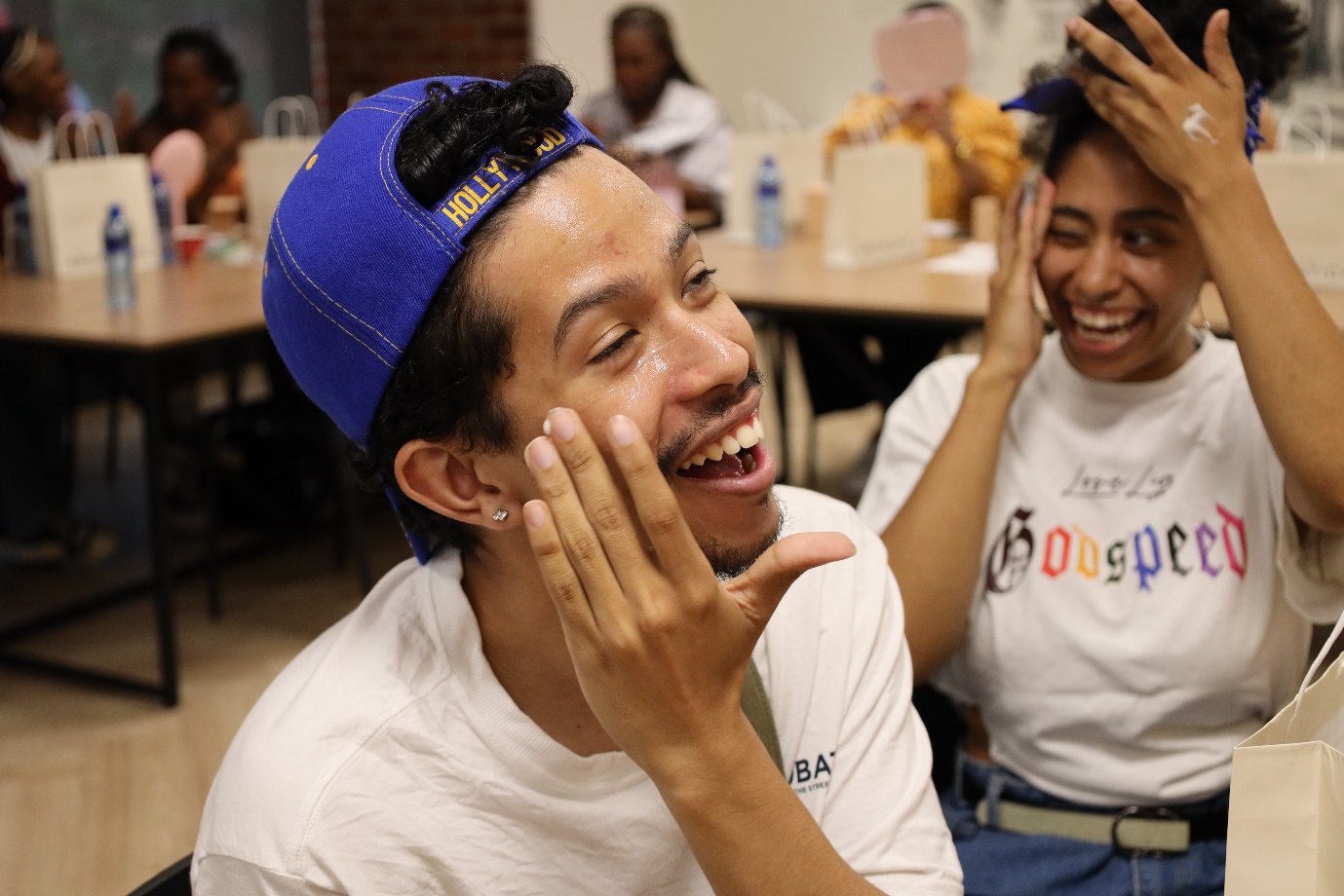 A person in a blue hat laughing

Description automatically generated