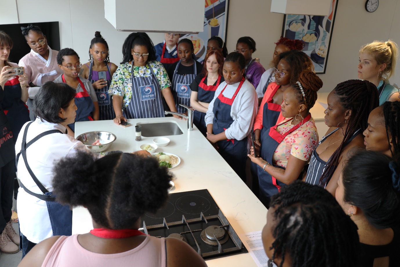A group of women in aprons standing around a table

Description automatically generated