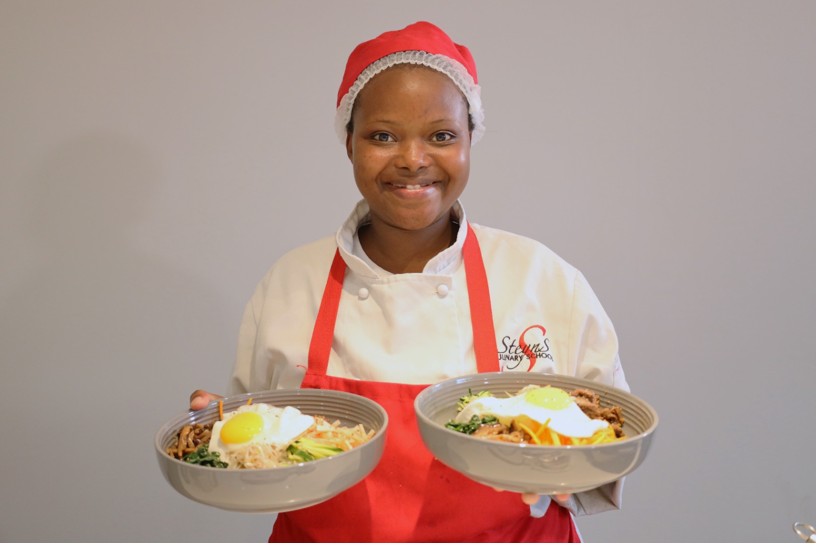 A person wearing a santa hat holding two plates of food

Description automatically generated