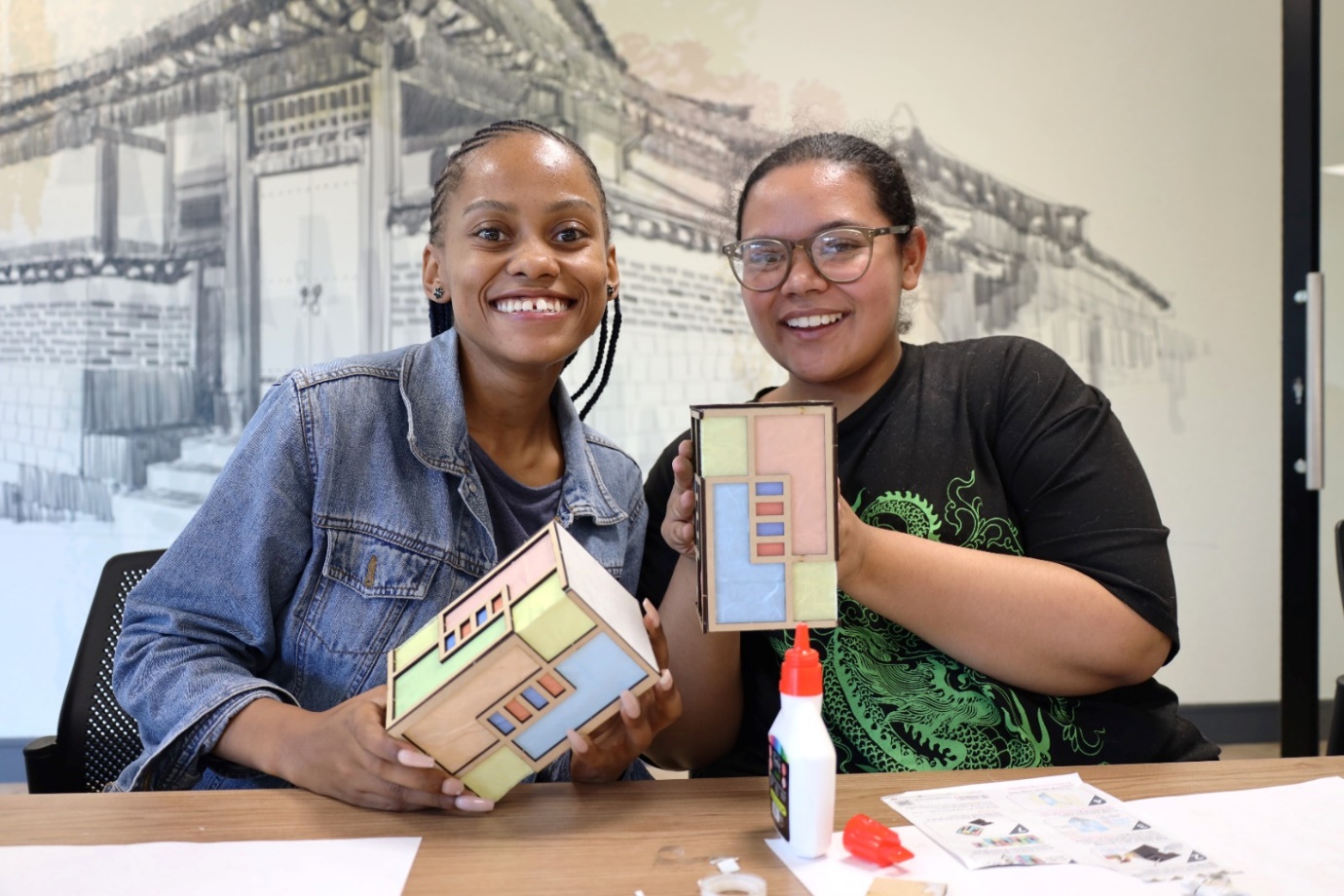 Two women holding a model of a house

Description automatically generated