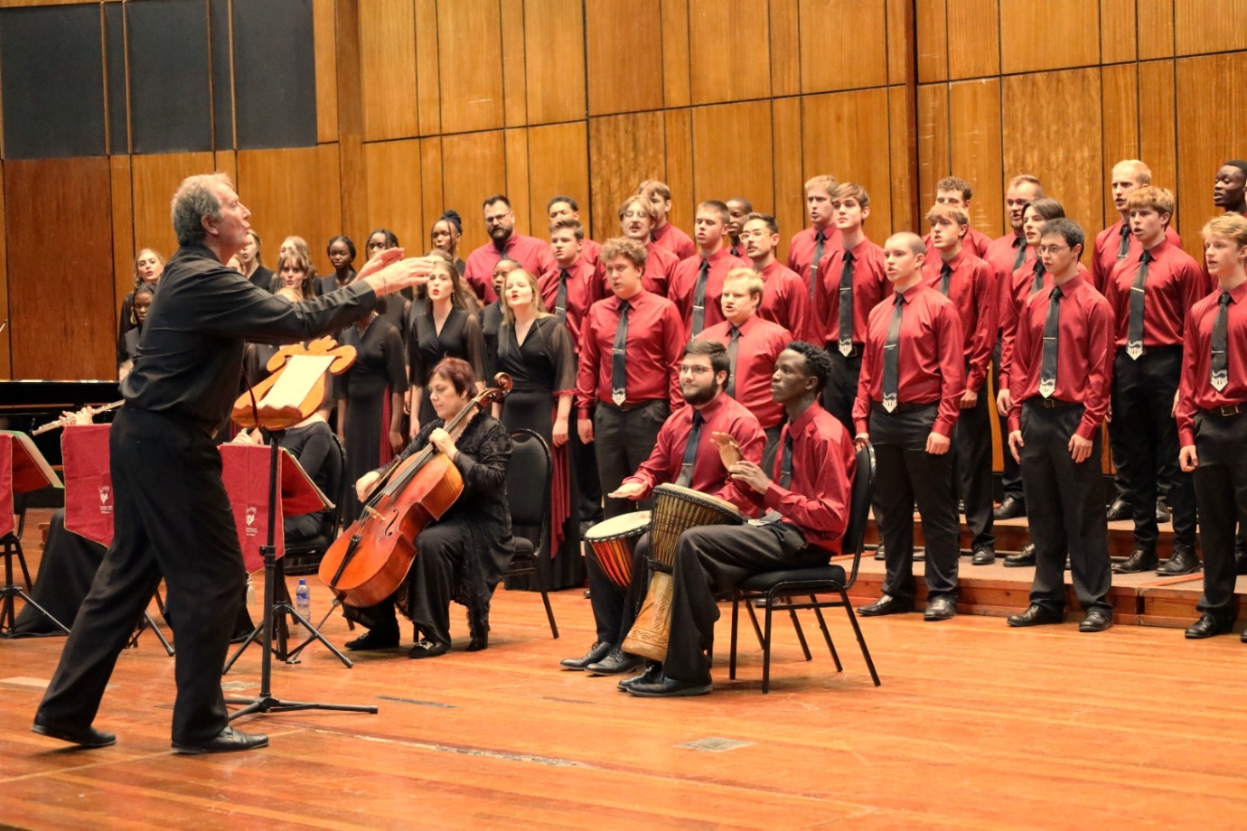 A person standing on a stage with a group of people playing instruments

Description automatically generated