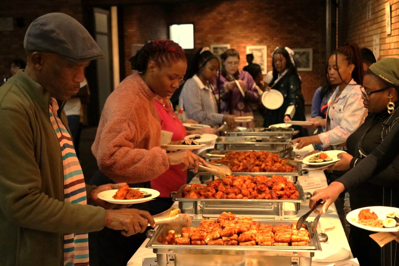 A group of people serving food

Description automatically generated