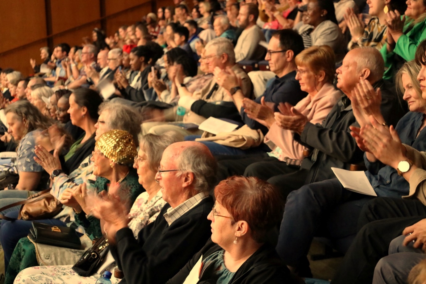 A group of people clapping in a auditorium

Description automatically generated