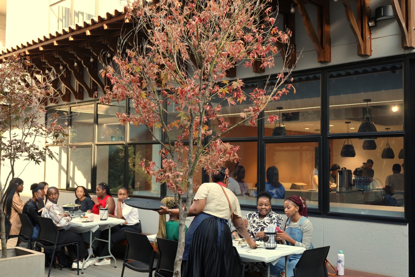A group of people sitting at tables outside a building

Description automatically generated