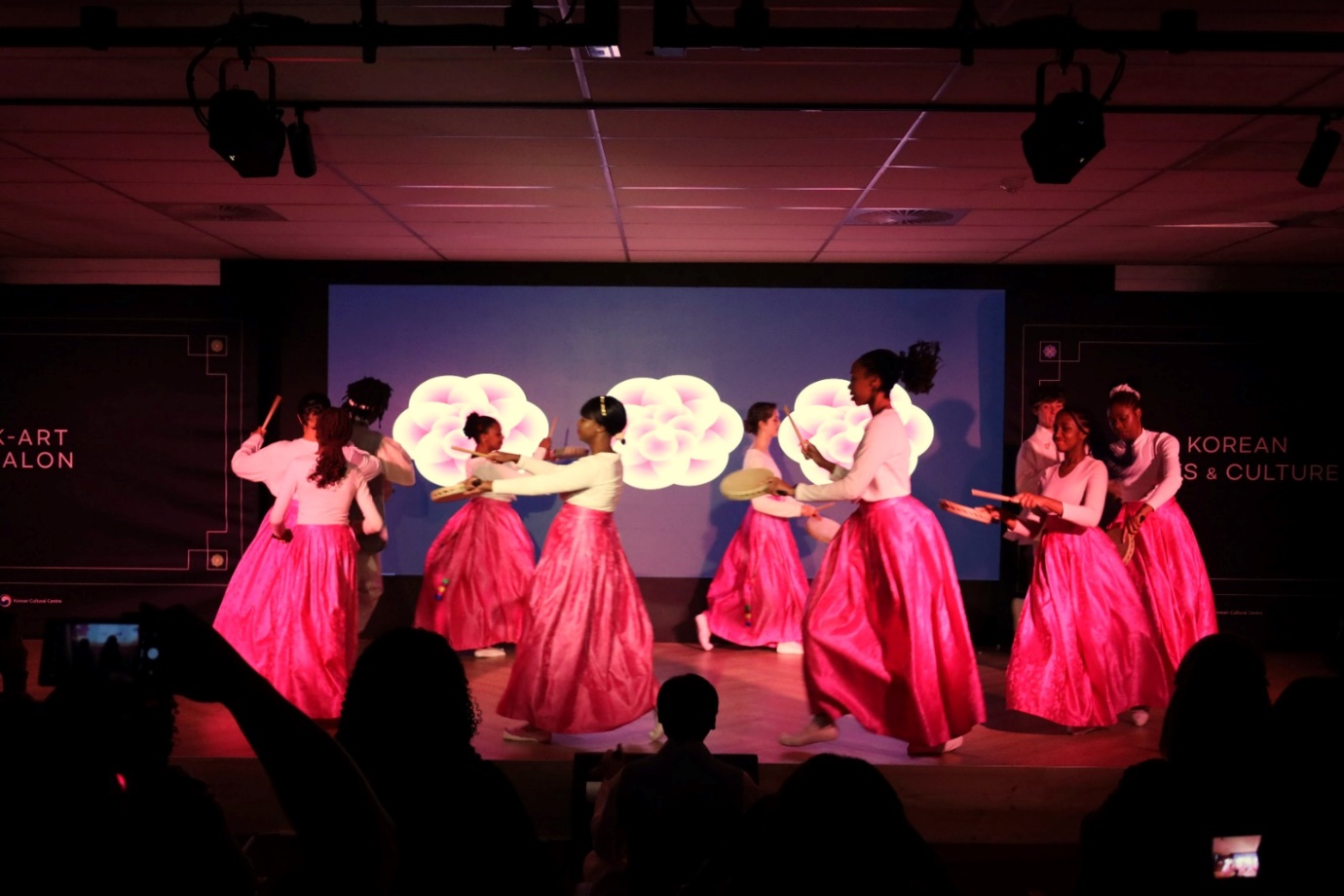 A group of women in pink skirts dancing on a stage

Description automatically generated