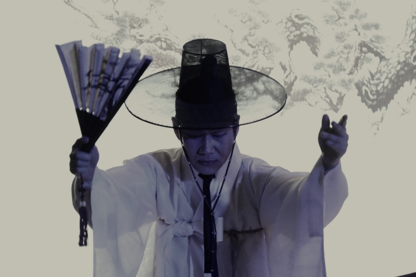 A person wearing a hat and holding a fan

Description automatically generated