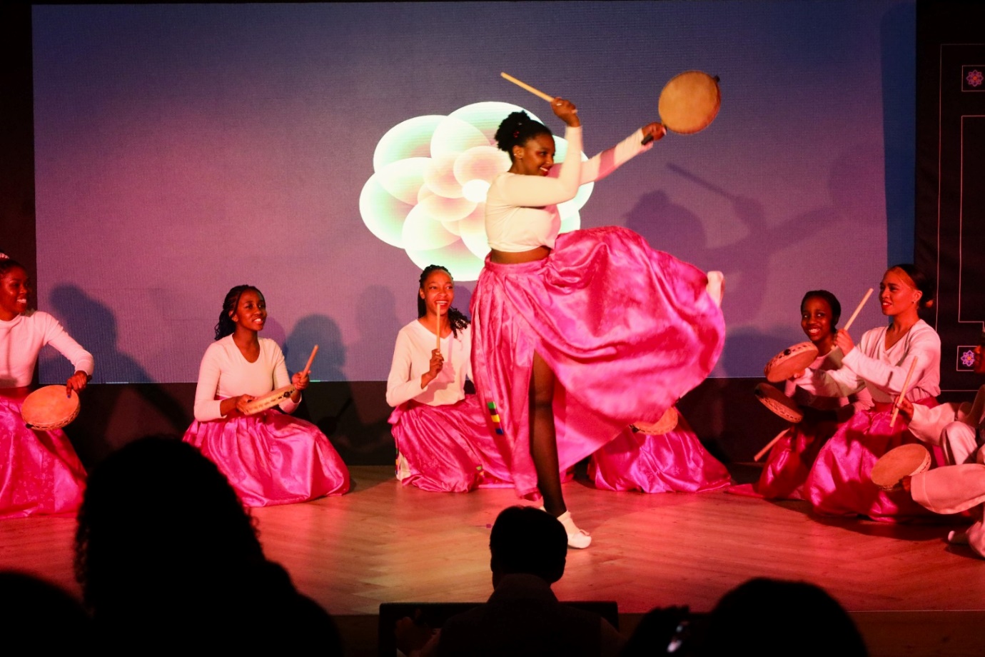 A group of women in pink skirts on a stage

Description automatically generated