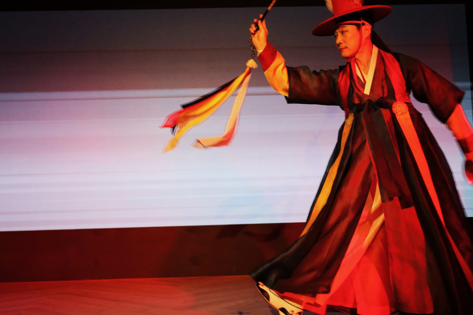 A person in a robe holding a whip

Description automatically generated
