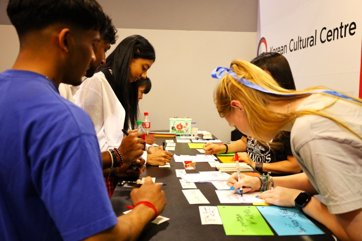 A group of people sitting at a table writing on paper

Description automatically generated