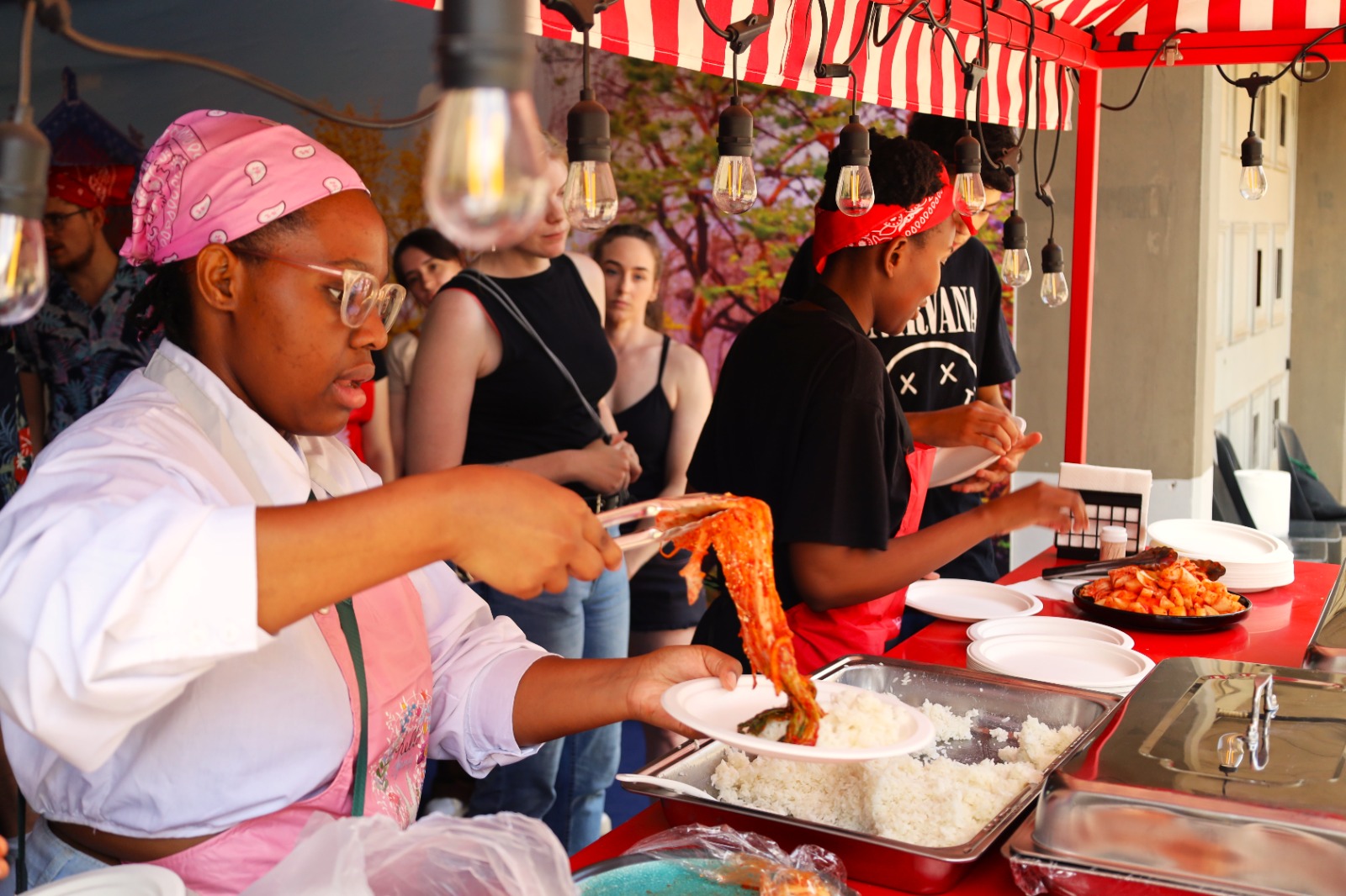 A group of people at a food stand

Description automatically generated