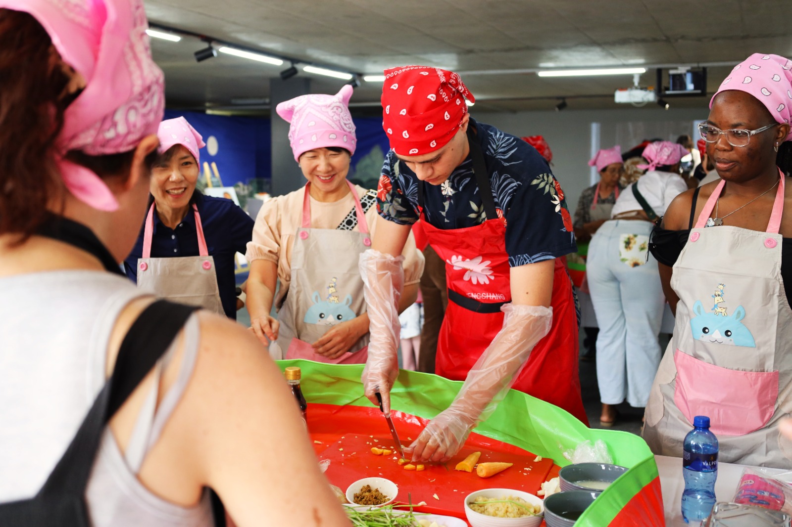 A group of people in aprons cutting food

Description automatically generated