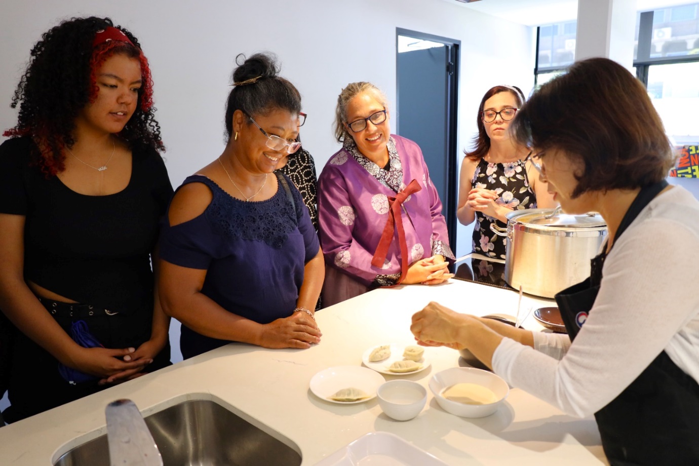 A group of women standing around a table

AI-generated content may be incorrect.