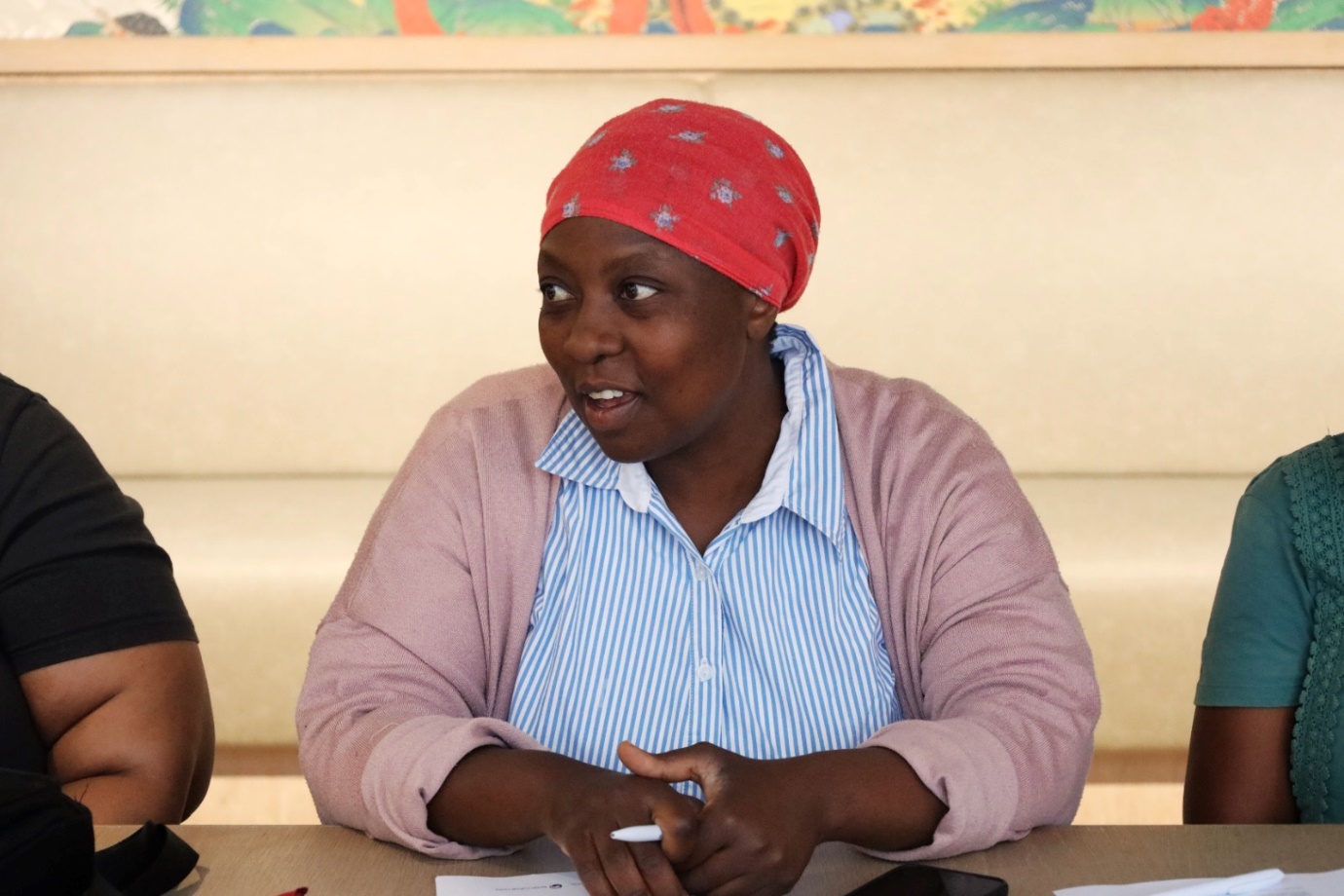 A person wearing a red head scarf sitting at a table

AI-generated content may be incorrect.