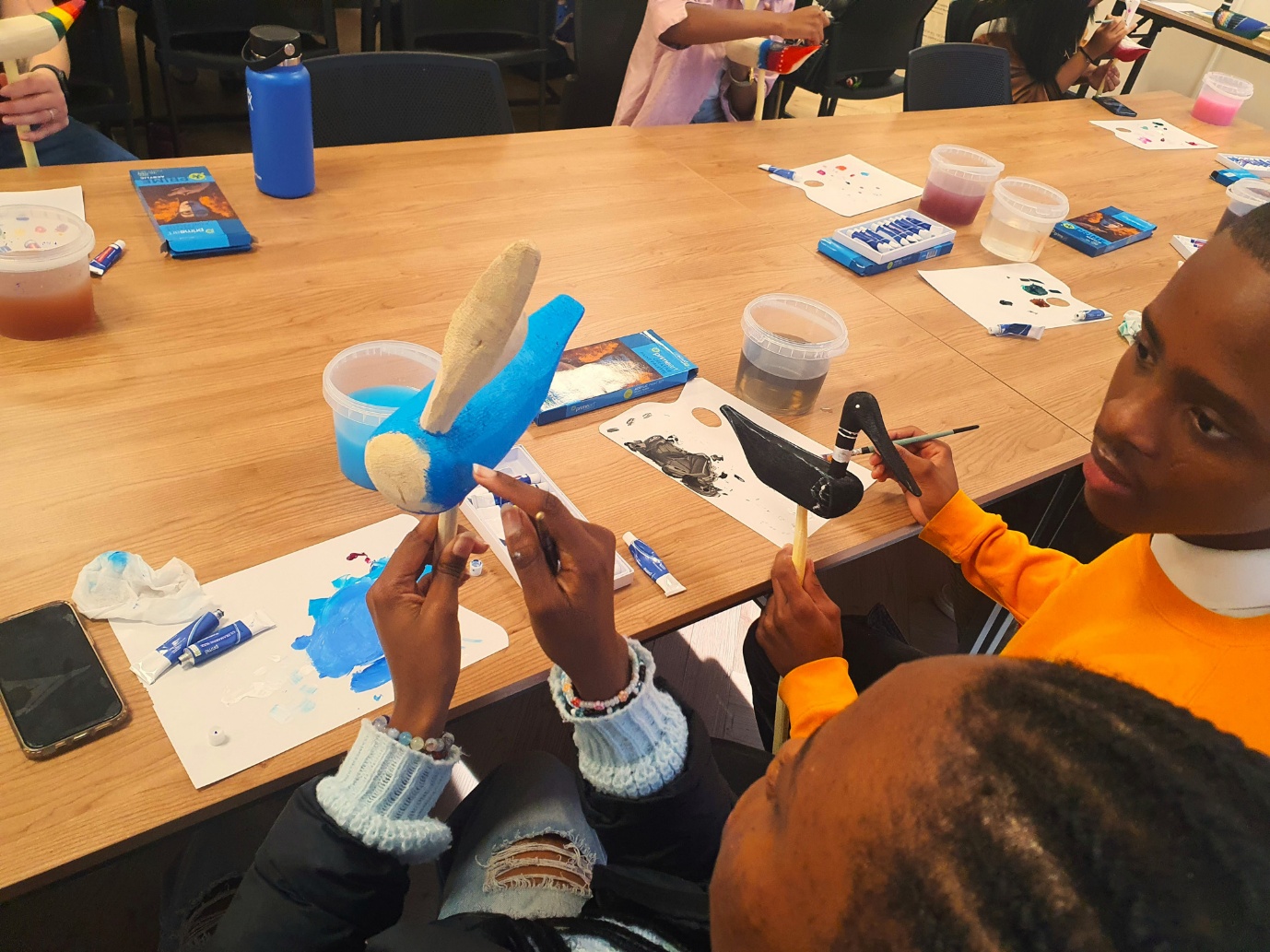 A group of people painting on a table

AI-generated content may be incorrect.