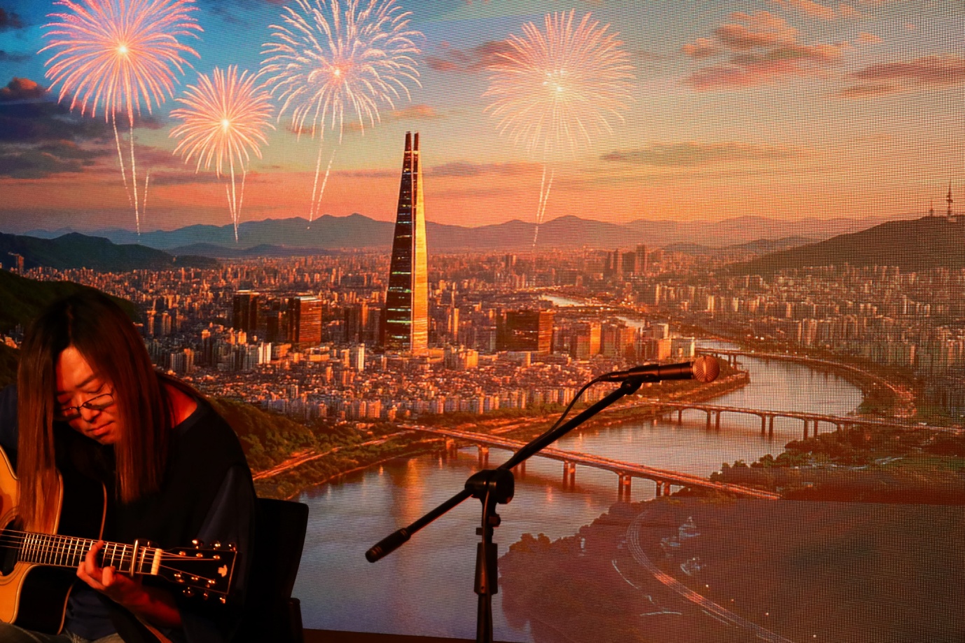 A person sitting in front of a microphone and a city with fireworks

AI-generated content may be incorrect.
