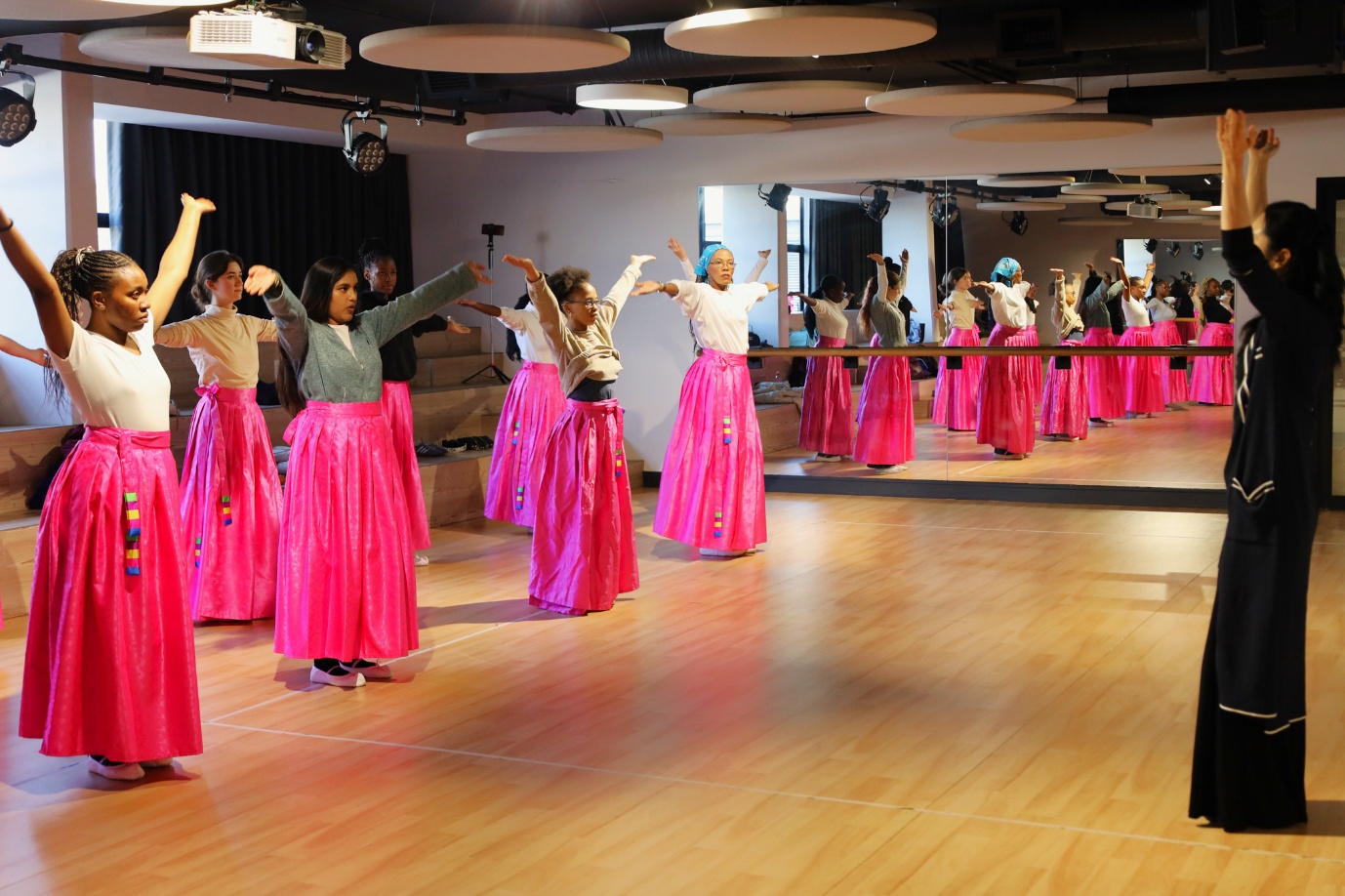 A group of women in pink skirts

AI-generated content may be incorrect.