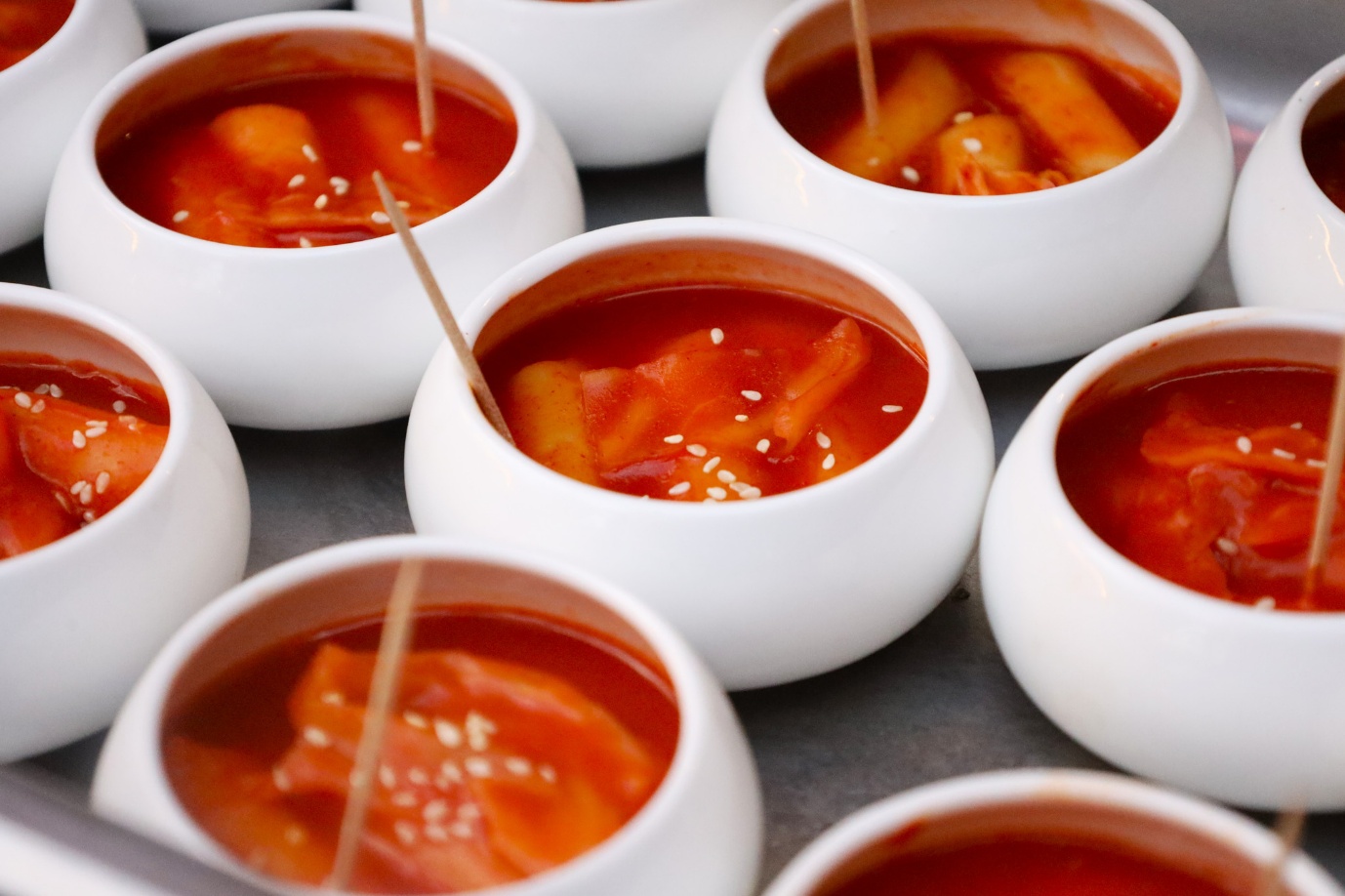 A group of white bowls with red soup

AI-generated content may be incorrect.