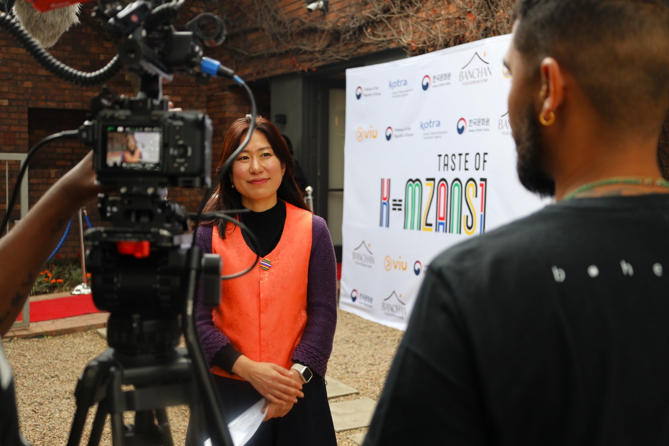 A person in an orange vest standing next to a person in front of a sign

AI-generated content may be incorrect.