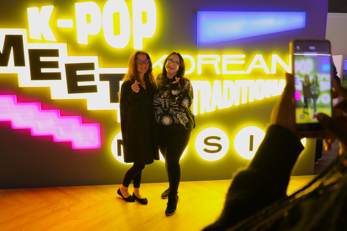 Two women standing in front of a neon sign

AI-generated content may be incorrect.