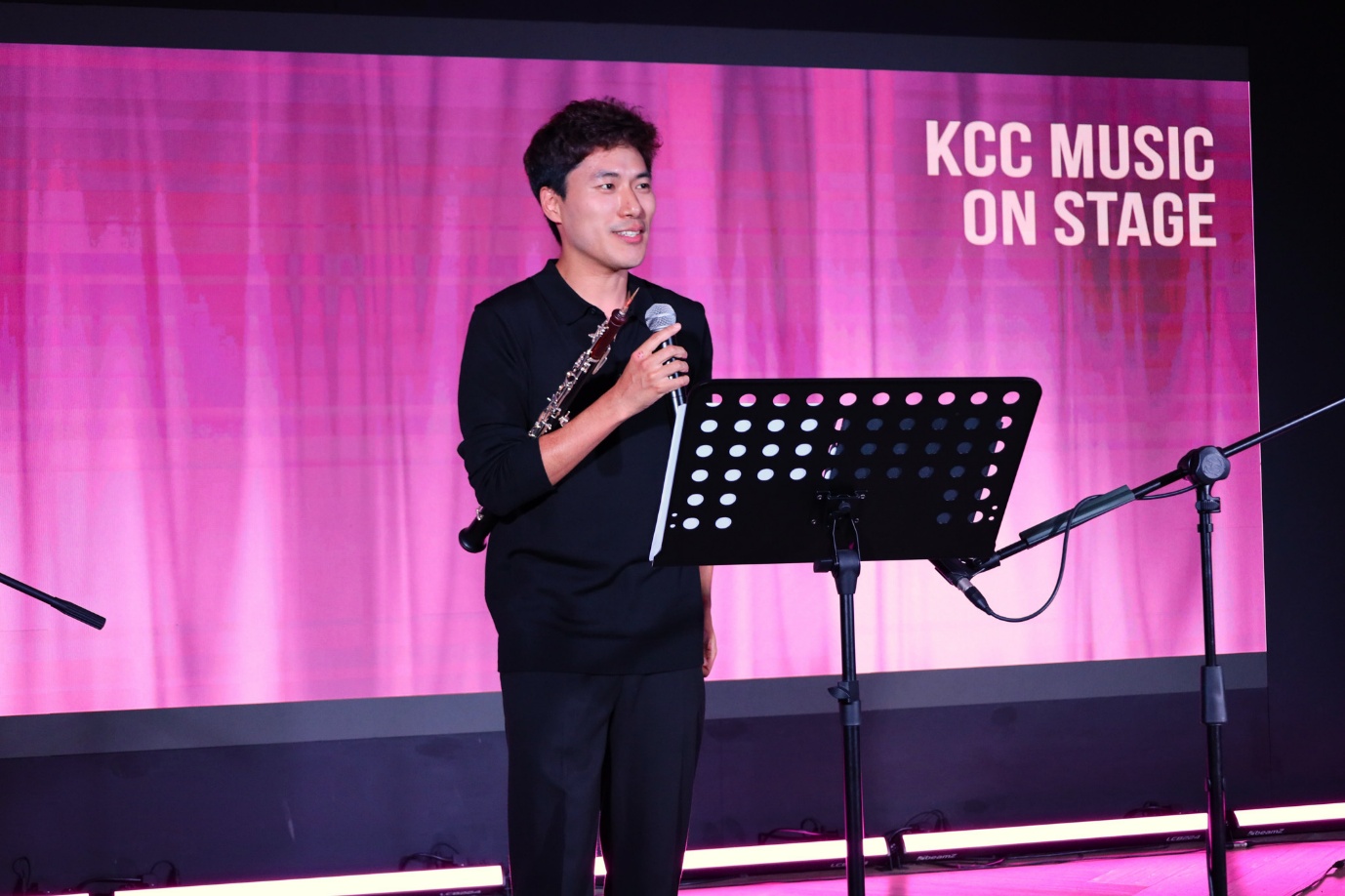 A person holding a microphone and standing on a stage
AI-generated content may be incorrect.